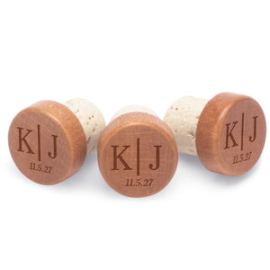 Personalized bottle stoppers engraved with initials separated by a line with a custom date below.