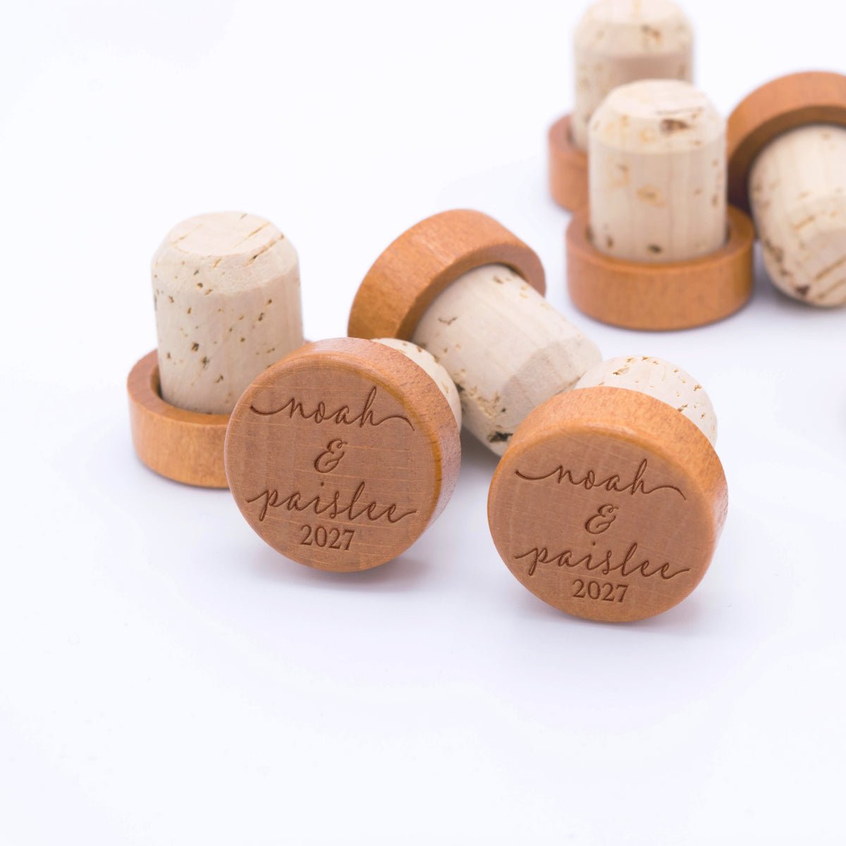 Engraved wooden wine bottle stoppers personalized with a couple's names and custom date.